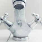 Bagno con rubinetto che perde, simbolo di spreco d'acqua e aumento bolletta.