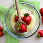 Crema pasticcera liscia e cremosa in una ciotola, con frusta e ingredienti sul tavolo.