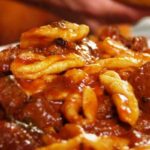 Pasta con ragù di salsiccia servita in un piatto decorato, pronta da gustare.