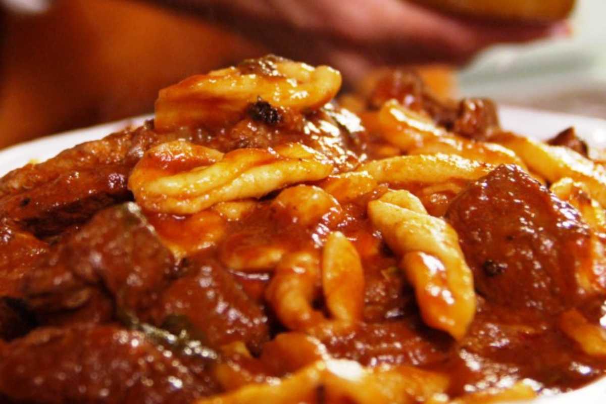 Pasta con ragù di salsiccia servita in un piatto decorato, pronta da gustare.