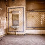 Piastrelle del bagno ingiallite, evidenziando segni di usura e macchie nel tempo.