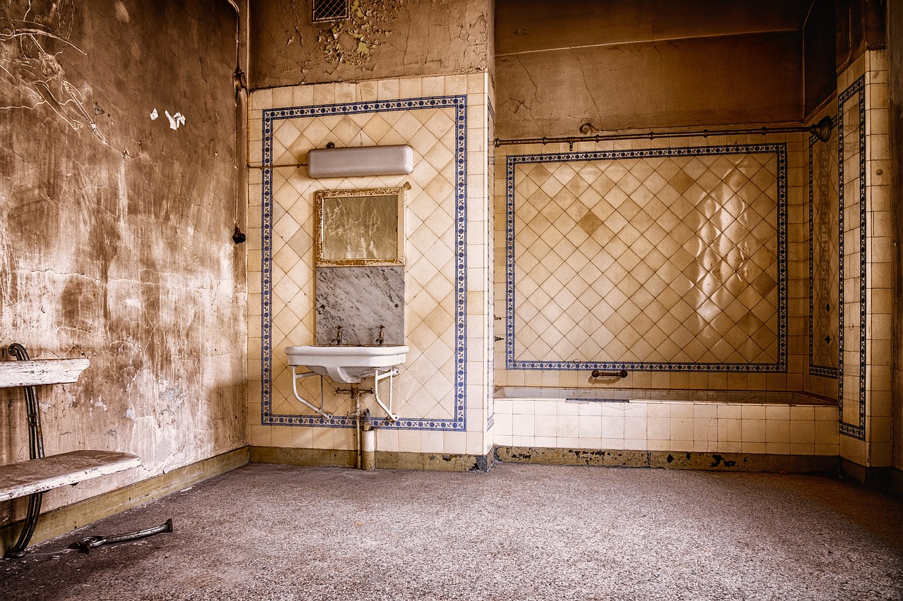 Piastrelle del bagno ingiallite, evidenziando segni di usura e macchie nel tempo.