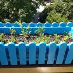 Orto rialzato su un balcone con piante verdi in vasi, ideale per coltivare in spazi ridotti.