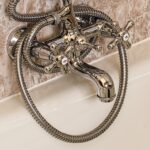 Immagine di tubi del bagno usurati con segni di perdite e corrosione, evidenziando la necessità di sostituzione.